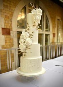 white wedding cake with gold leaves and dress detail