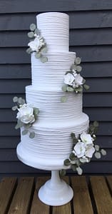 white wedding cake with ridged icing and sugar flowers