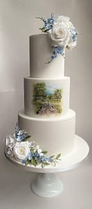 painted scene on white wedding cake with blue and white flowers